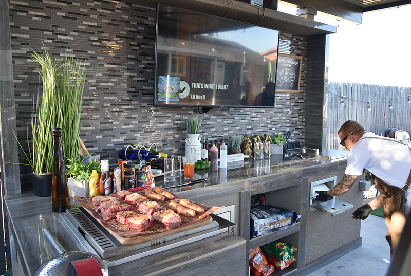 Outdoor kitchen with grilling area and TV mounted on the wall