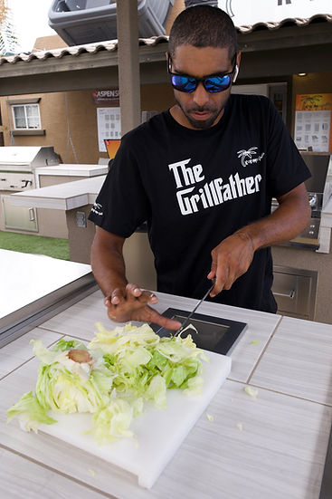 Man preparing food on a grill with 'The Grillfather' t-shirt