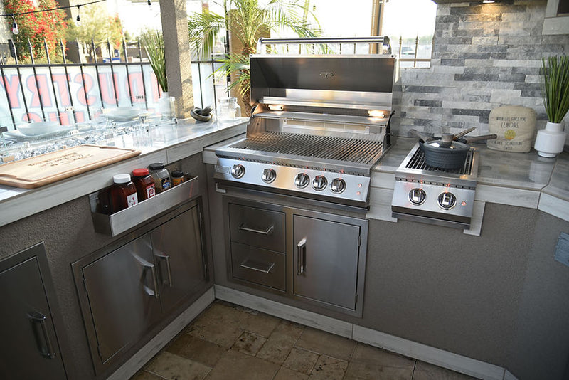 Outdoor kitchen with stainless steel grill and stove on a patio