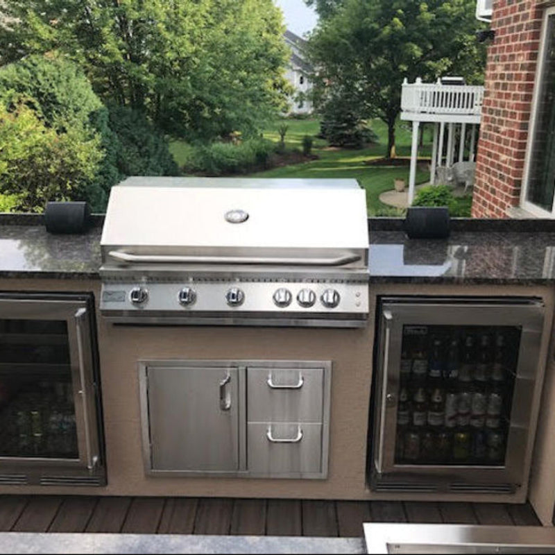 Outdoor kitchen with stainless steel grill and beverage coolers on a patio