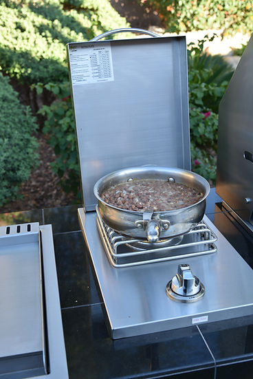 Outdoor cooking setup with a portable stove and pan on a patio