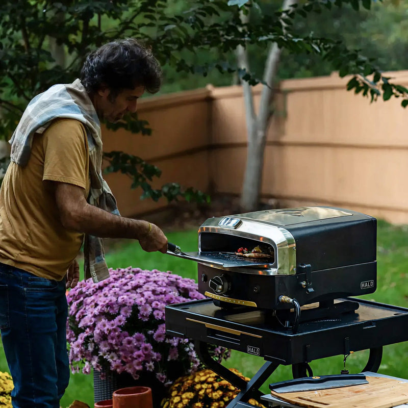Collapsible outdoor cooking cart fully set up on backyard patio