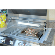 Stainless steel outdoor grill with food on a countertop