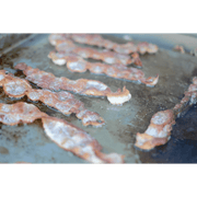 Bacon frying on a griddle with a green border