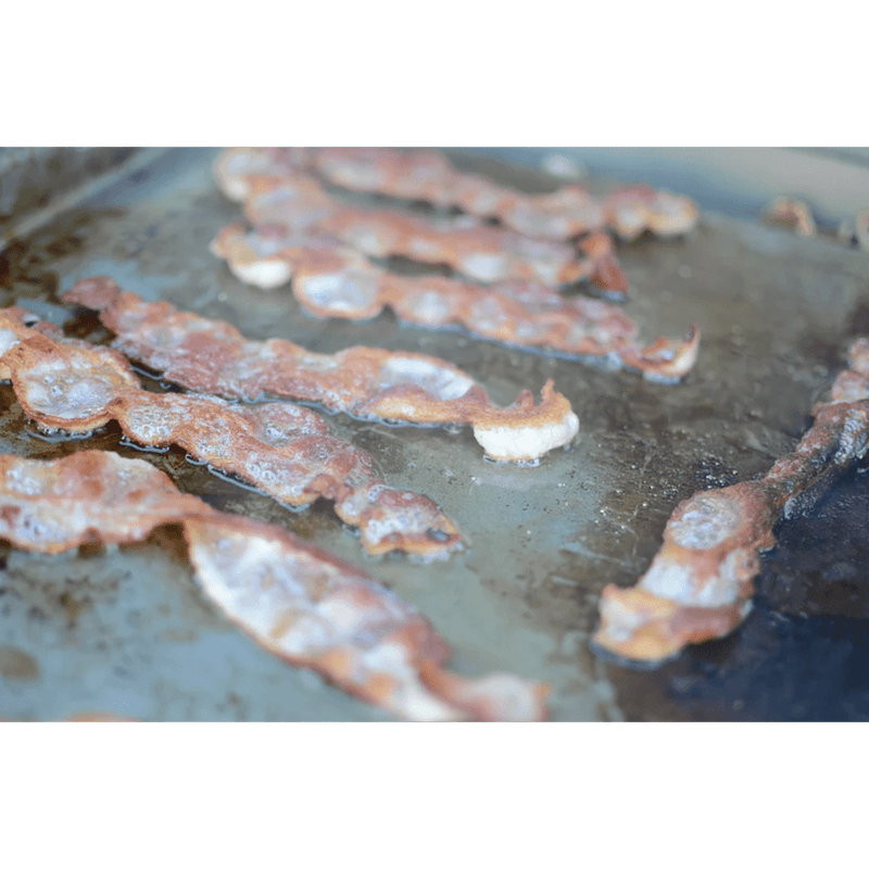 Bacon frying on a griddle with a green border