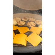 Cheese slices and waffle-like items cooking on a grill