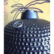 Black textured barbecue grill with a thermometer on a patterned background